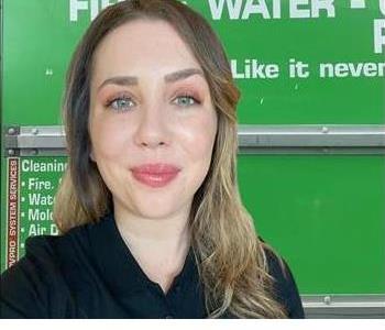 Woman in black shirt in front of green truck