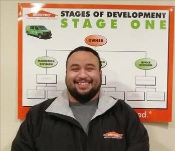 Male employee with black hair and Servpro poster in the background. 